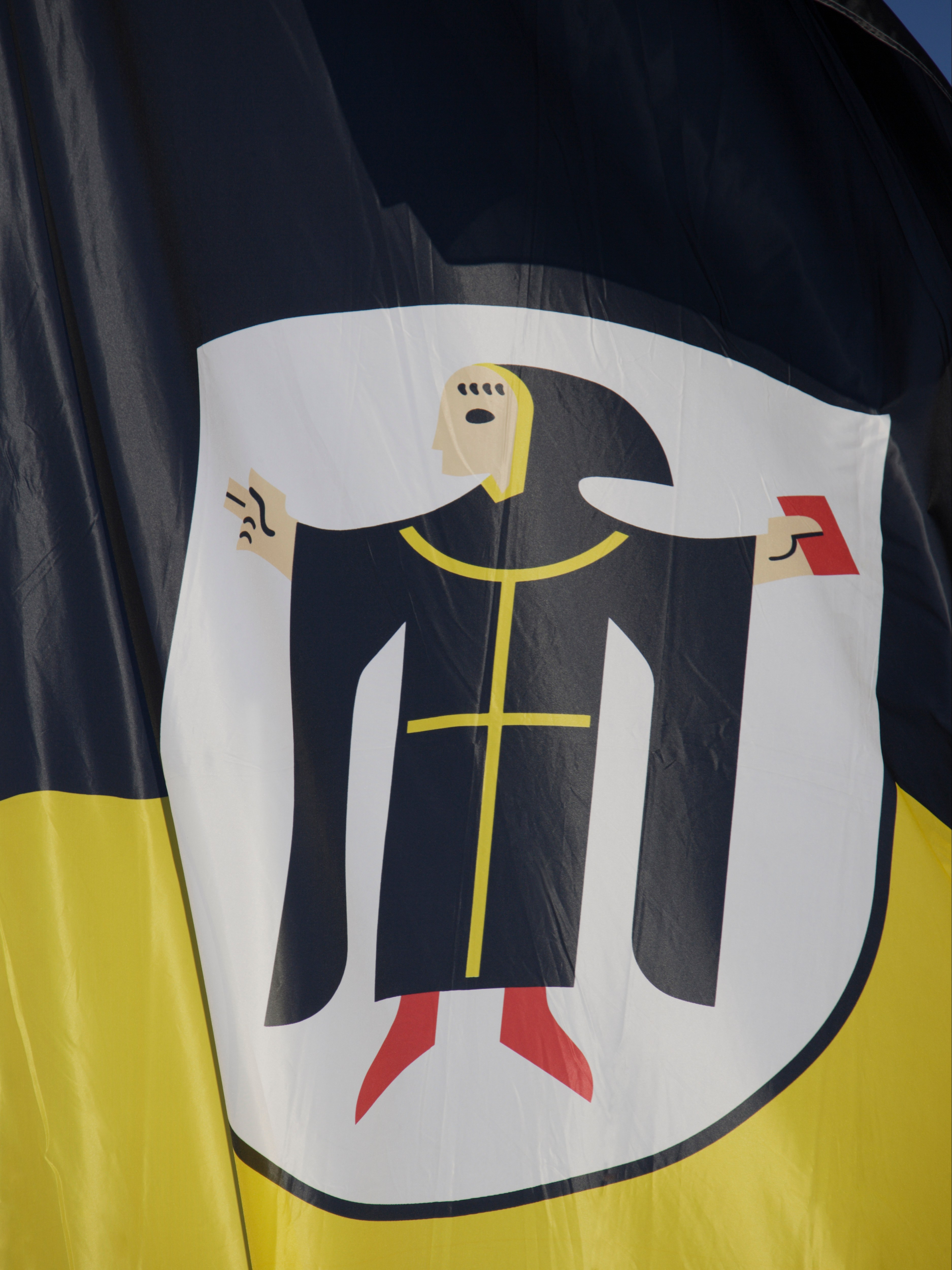 Un Münchner Kindl sur un drapeau noir et jaune, le symbole de Munich