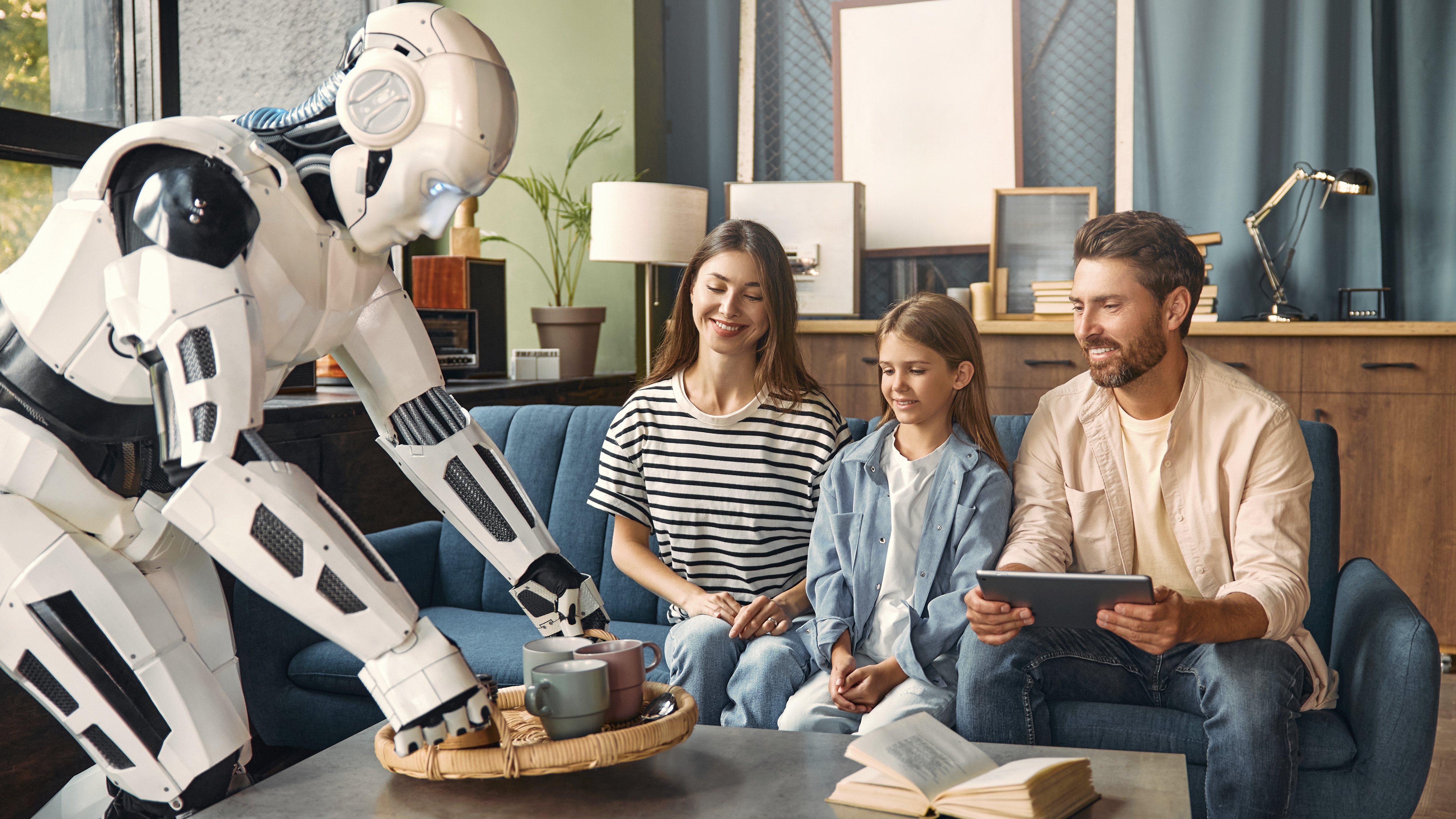 Un père et son enfant sont assis sur un canapé bleu et rient. Un robot blanc leur propose des boissons sur un plateau, tandis que le père utilise une tablette. Un livre ouvert est posé sur la table. La lumière chaleureuse crée une atmosphère à la fois futuriste et détendue.